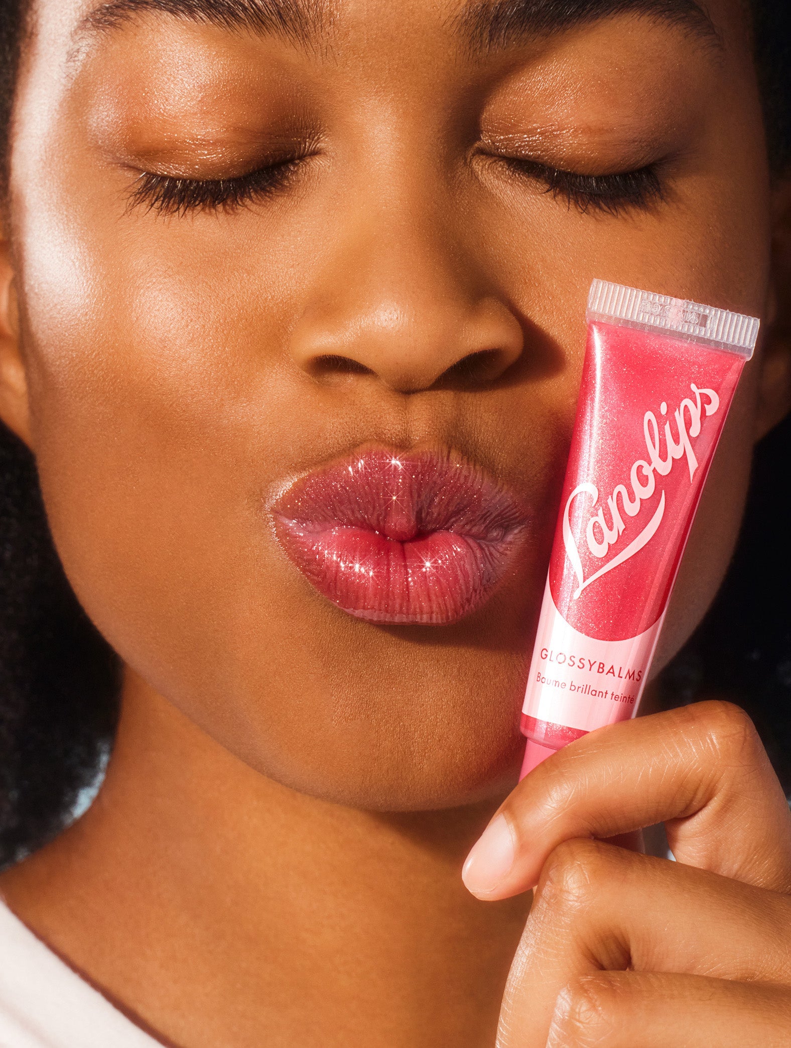 Model shot of a model holding the Lanolips Glossy Balms candy tube.
